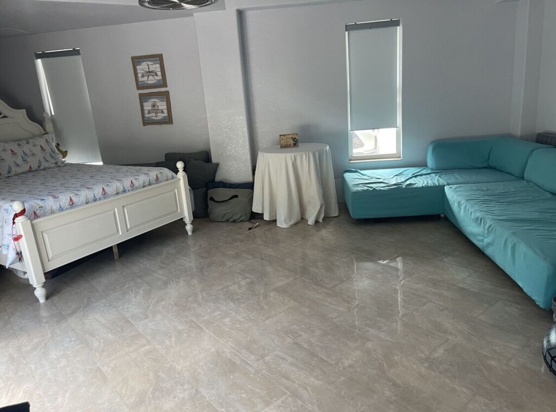 A bedroom with a bed, a sofa, a small table, and a window.