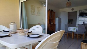 A dining area with a white table set for four, white chairs, and a kitchen in the background. - Splendid sea view for this T2 in residence with swimming pool - 4GOEL248 (SAINT CYPRIEN PLAGE)