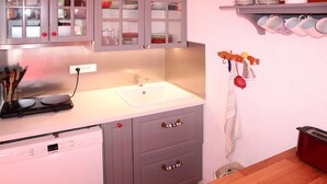 Een keuken met een witte spoelbak, grijze kastjes en een Bosch vaatwasser.