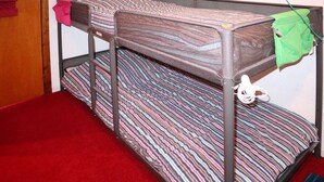 Een stapelbed met gestreept beddengoed en een rode vloerbedekking.