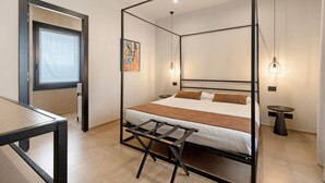 Un lit à baldaquin avec une couverture marron, une petite table et une lampe fixée au mur.