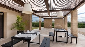 Une terrasse extérieure avec des tables et des bancs, un pot de fleurs et une vue sur le paysage.
