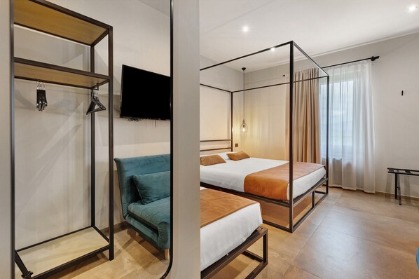 Een kamer met een bed, een bank, een televisie en een kledingkast.