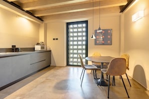 Une cuisine moderne avec un coin repas, comprenant une grande fenêtre, une table à manger avec des chaises et un luminaire suspendu.