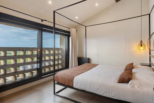 A modern bedroom with a large window, a bed, and a nightstand.