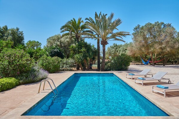 A rectangular swimming pool with clear blue water, surrounded by lounge chairs and palm trees. - Finca 'Son Garreta' with Views of the Tramuntana, Private Pool and Wi-Fi (El Palmer)