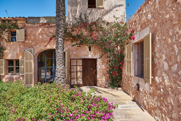 A stone building with arched doorways, a wooden door, and shutters.