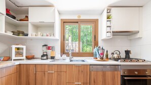 Een moderne keuken met houten kastjes, een ingebouwde vaatwasser, een fornuis en een raam met uitzicht op groen.