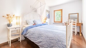 Een slaapkamer met een bed, nachtkastje en raam met uitzicht.