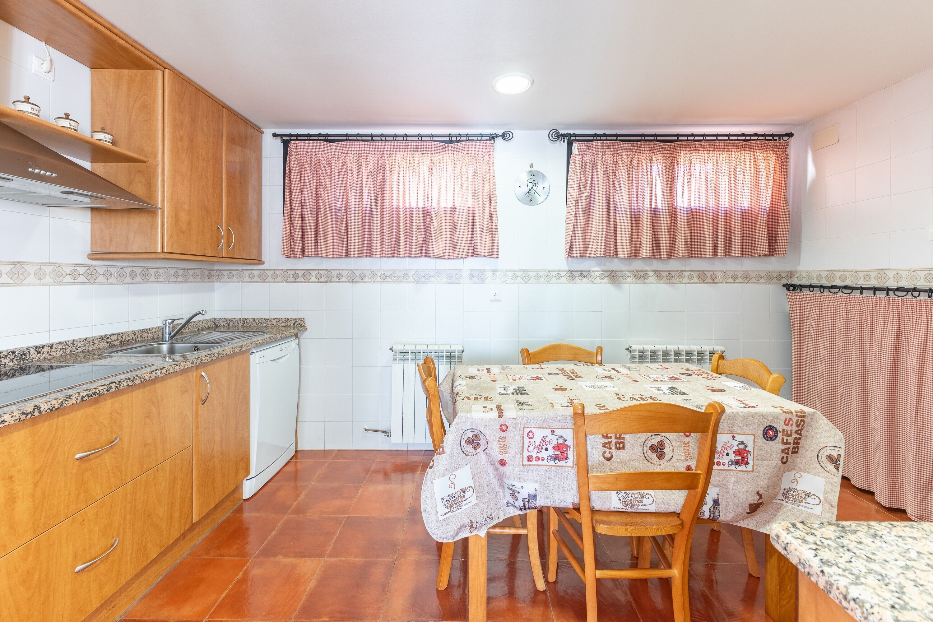 Une cuisine avec des meubles de rangement en bois, un four encastré, un évier et une table à manger avec des chaises.