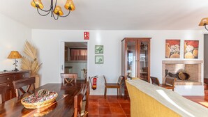 Un comedor con una mesa de madera, sillas, una cesta tejida y un extintor.
