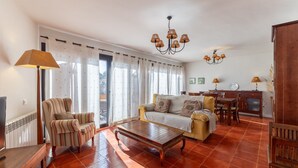 Una sala de estar con sofá, sillón, mesa de centro y comedor con mesa y sillas.