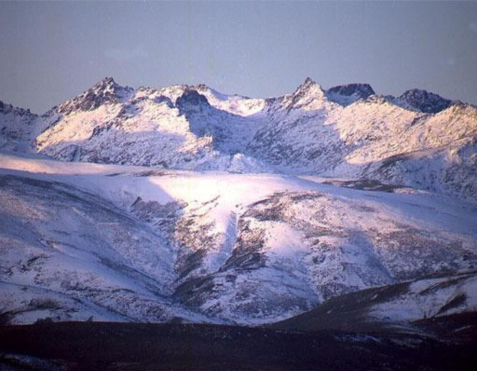 Eine gebirgige Landschaft mit schneebedeckten Gipfeln und einem Tal.