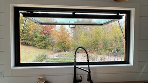 A kitchen with a window, two pendant lights, and a sink.