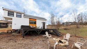 A two-story house with a deck, outdoor seating, and a fire pit.