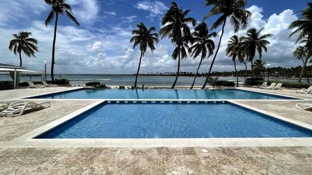 A swimming pool with palm trees and a view of the ocean. - Escape to the beach, live the luxury. Nueva Romana Beach. (San Pedro de Macorís)