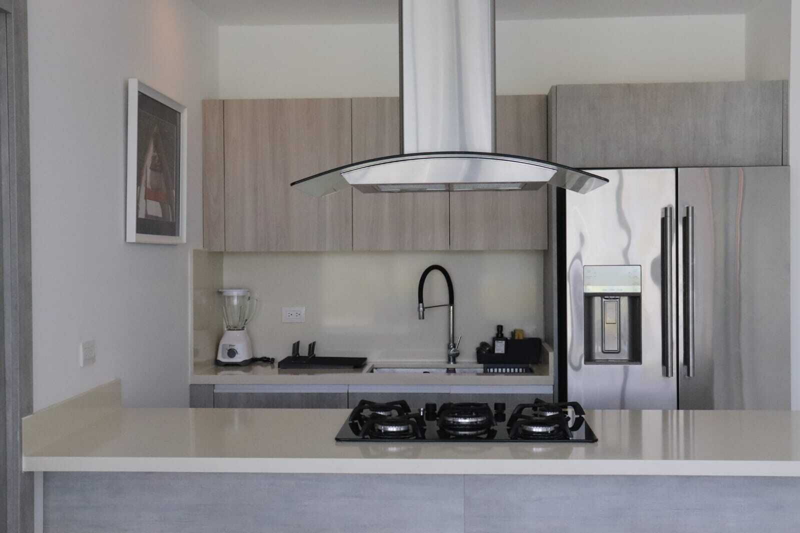 Eine moderne Küche mit Gasherd, Mixer, Spüle und Kühlschrank.