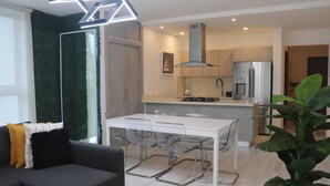 A modern kitchen with a white table and chairs, a built-in stove, and a refrigerator. - Escape to the beach, live the luxury. Nueva Romana Beach. (San Pedro de Macorís)