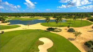 A golf course with sand bunkers, water hazards, and palm trees. - Escape to the beach, live the luxury. Nueva Romana Beach. (San Pedro de Macorís)