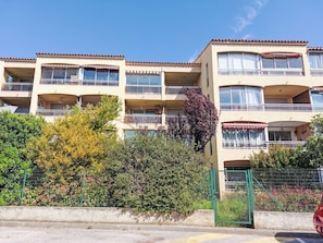 Un immeuble à plusieurs étages doté de balcons, d’une entrée sécurisée et surplombant un ciel dégagé.