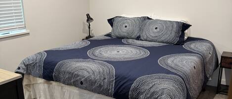 A bedroom with a bed, a desk, a lamp, and three wall art pieces.