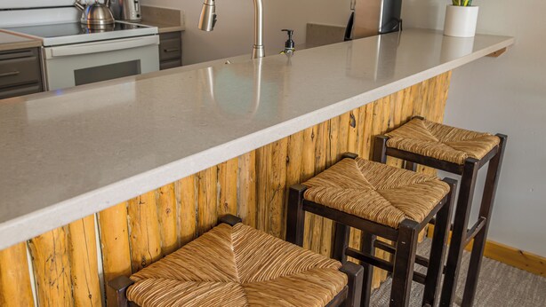Een keuken met een groot eiland, roestvrijstalen apparatuur en houten details.