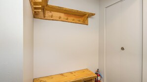 Een hoek van een kamer met een houten bankje en een wandplank.