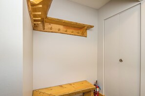 A corner of a room with a wooden bench and a wall-mounted shelf.