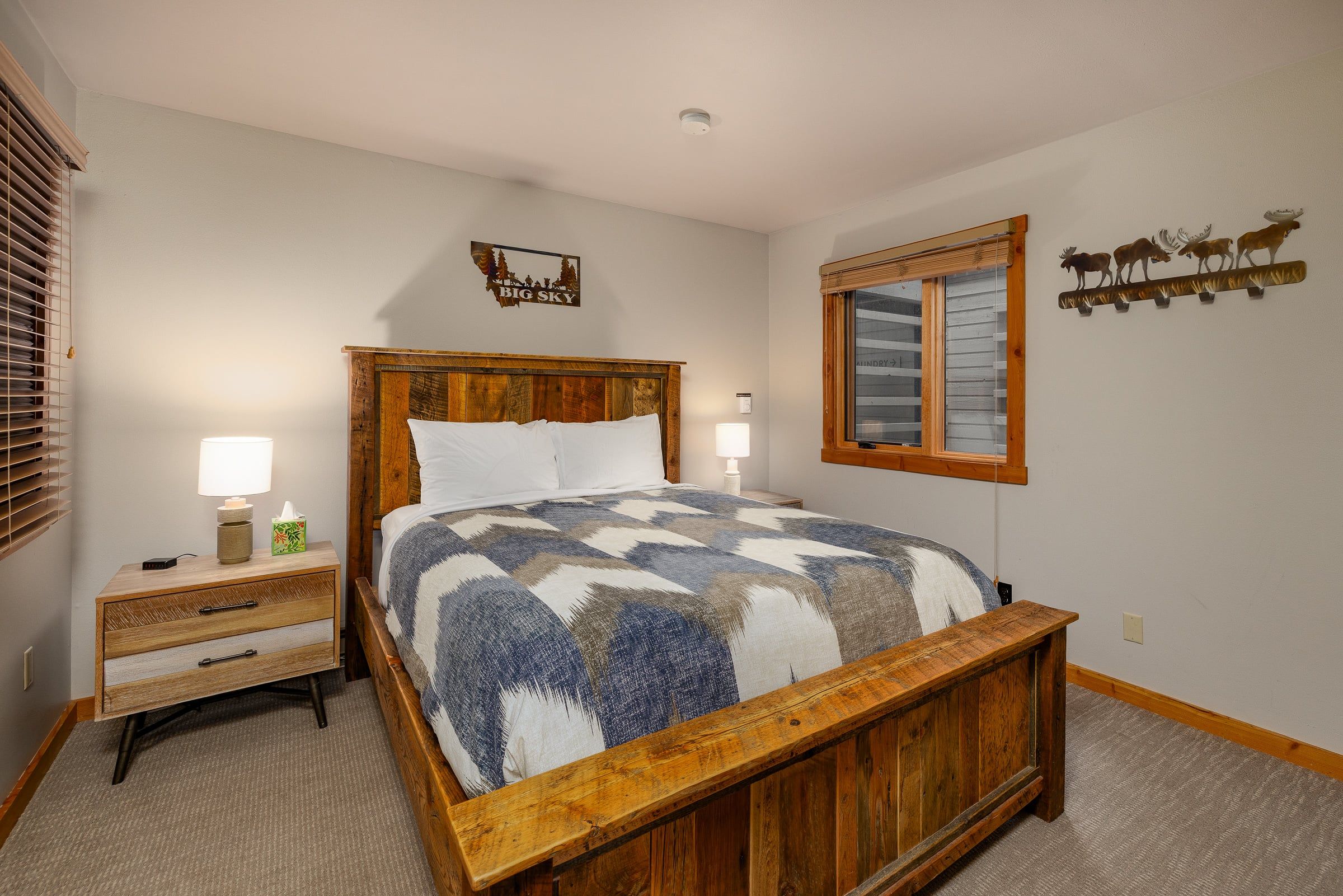 A bedroom with a wooden bed, bedside tables, a window, and wall decorations.