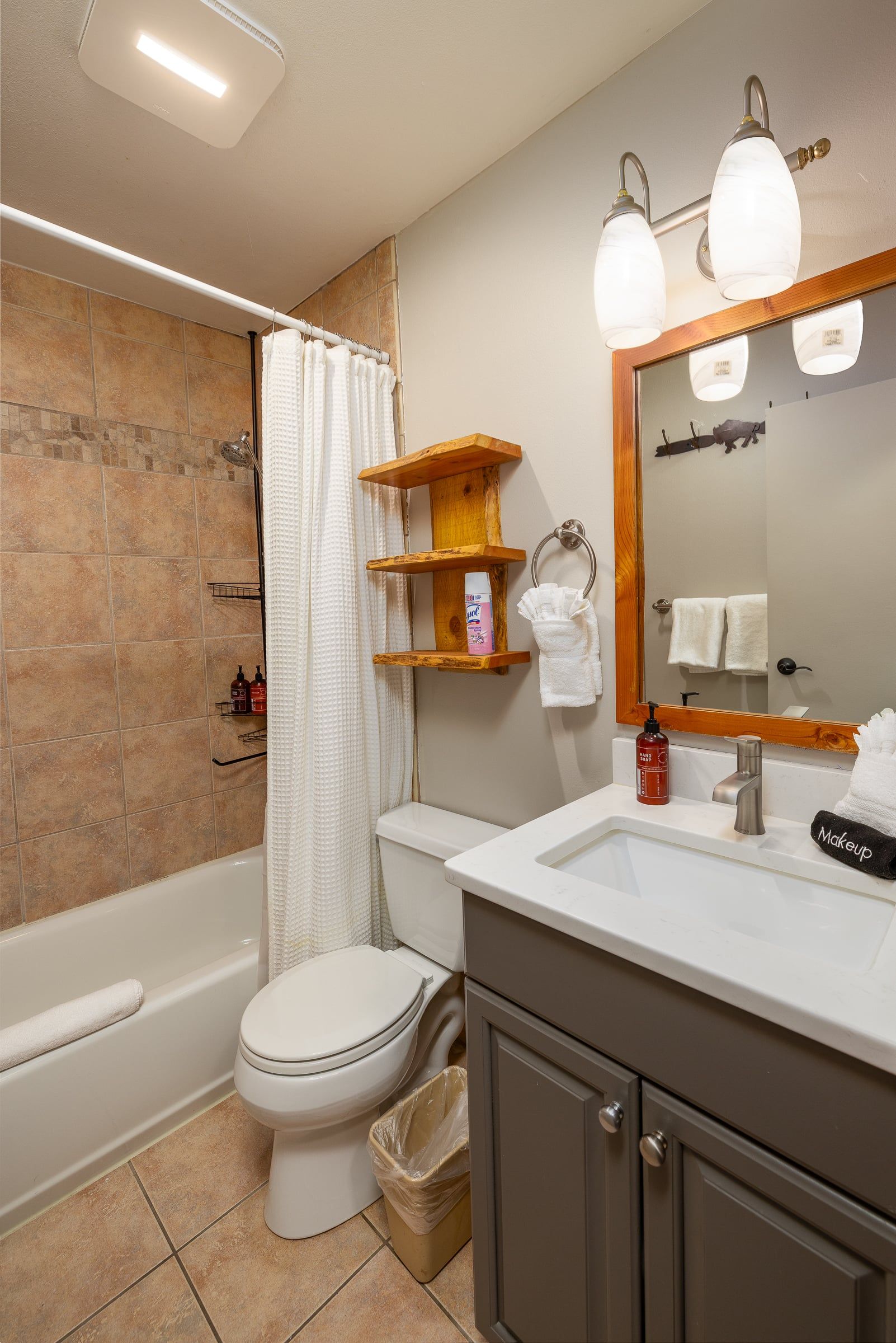 A bathroom with a bathtub, toilet, vanity with a mirror, and a shower curtain.
