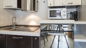 A modern kitchen with a stainless steel range hood, a built-in microwave, and a coffee maker. - Rododendro by Interhome (Madesimo)