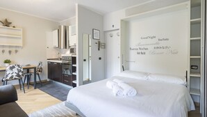 A modern hotel room with a large bed, a small desk, and a kitchenette. - Rododendro by Interhome (Madesimo)