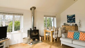 A cozy living room with a fireplace, a dining area, and a sofa.