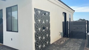 A modern house with a geometric-patterned wall, a black gate, and a paved driveway.