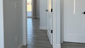 A hallway with a wooden floor, white walls, and a door with a black handle.