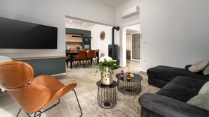 A modern living room with a flat-screen TV, leather chairs, a black sofa, and a dining area with a wooden table and chairs. - Villa Canziana (Istria - Pula) (Pula)