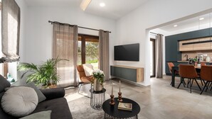 A modern living room with a sofa, a dining table, and a kitchen area. - Villa Canziana (Istria - Pula) (Pula)