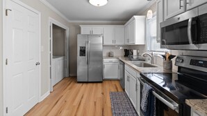 A modern kitchen with white cabinets, stainless steel appliances, and a wooden floor. - Tranquil Retreat Near Lake Norman – Cozy, Spacious & Perfect for Relaxation! (Denver)