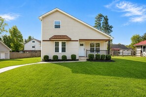 A two-story house with a front porch, a garage, and a well-maintained lawn. - Tranquil Retreat Near Lake Norman – Cozy, Spacious & Perfect for Relaxation! (Denver)