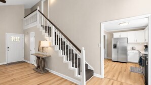 A modern kitchen with stainless steel appliances, a wooden floor, and a staircase with white railings. - Tranquil Retreat Near Lake Norman – Cozy, Spacious & Perfect for Relaxation! (Denver)