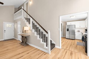 A modern kitchen with stainless steel appliances, a wooden floor, and a staircase with white railings. - Tranquil Retreat Near Lake Norman – Cozy, Spacious & Perfect for Relaxation! (Denver)