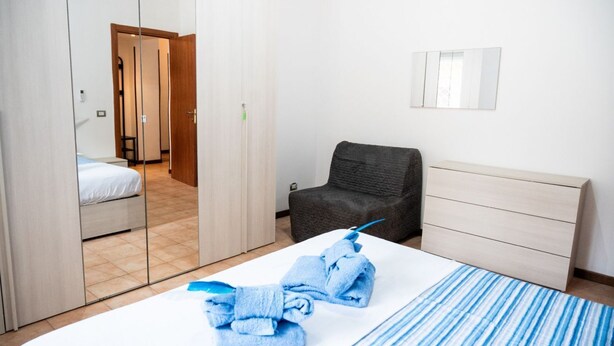 Una habitación de hotel con una cama, una silla, un aparador y un espejo en la pared.