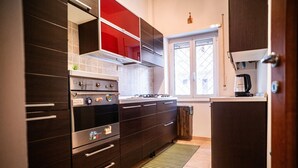 Cocina moderna con armarios oscuros, electrodomésticos de acero inoxidable y una ventana con persianas.