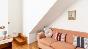 Una sala de estar moderna con un sofá, una lámpara, un cuadro enmarcado y una escalera.
