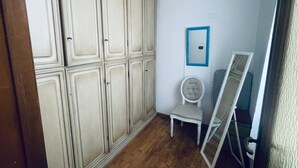 Una habitación con armario, una silla y un espejo apoyado en la pared.
