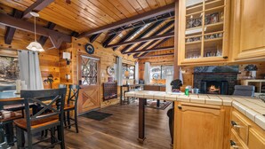 Un interior de madera con comedor, cocina y chimenea.