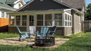 A covered patio with a fire pit, two blue Adirondack chairs, and a table.