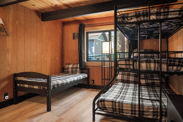 Une chambre avec un lit superposé, des murs en bois et une fenêtre.