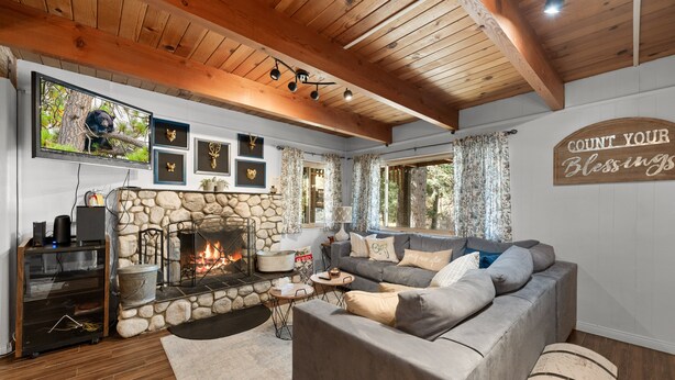 A cozy living room with a stone fireplace, a comfortable sofa, and a television mounted on the wall.