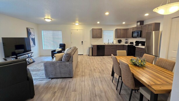A modern apartment with a living room, dining area, kitchen, and a large TV. - Hill Base Modern (Umatilla)